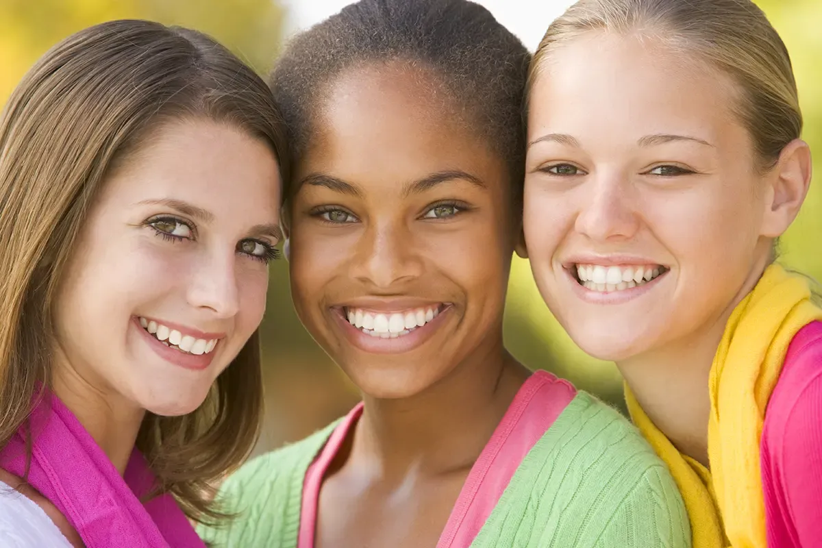 Three smiling teen girls with straight teeth