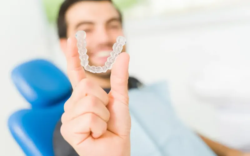 Smiling man holding aligners